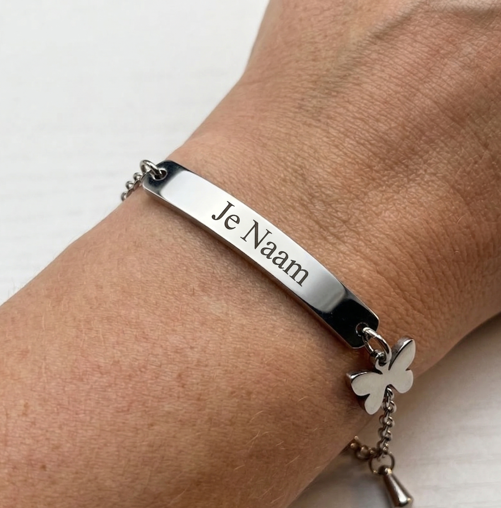 Armband - gepersonaliseerd - zilverkleurig - met vlinderbedel - gebogen naamplaatje - verstelbaar